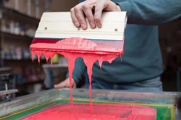 male doing custom screen printing in red color at habit fit sports factory in Sialkot Pakistan