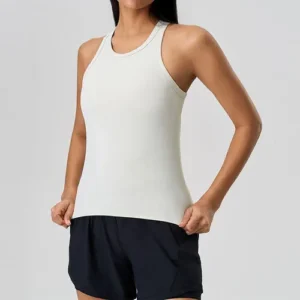 A front view of a woman wearing a crisp white, form-fitting racerback tank top paired with dark navy athletic shorts.